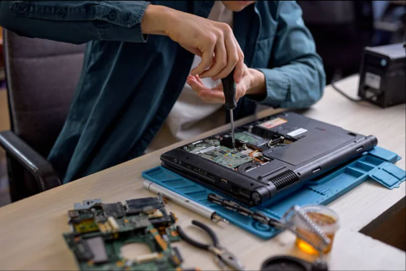 Technician repairing a laptop with a precision screwdriver