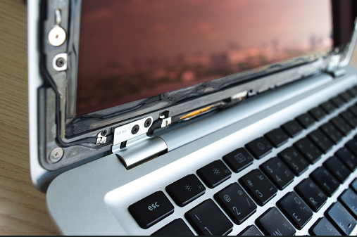 Close-up of a laptop hinge and display assembly being repaired